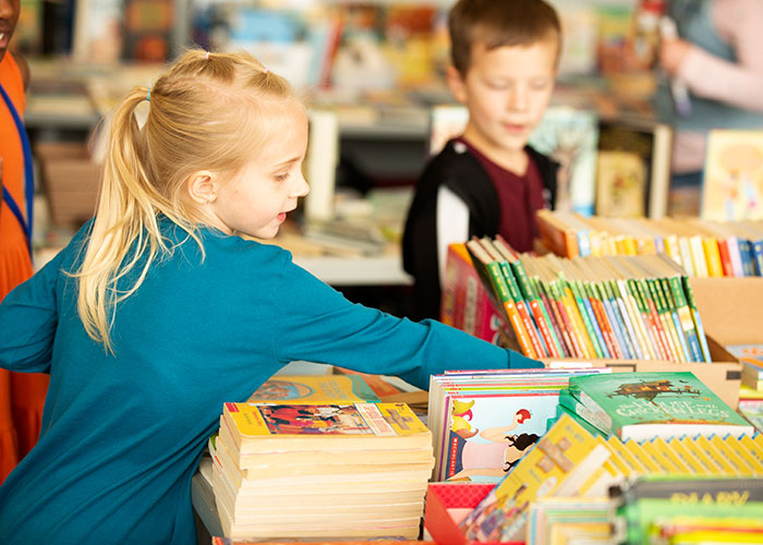 Kid picks out book from table full of books