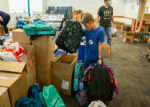 Volunteer places backpacks in boxes at Stuff The Bus